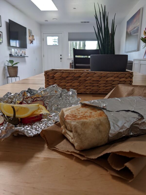 A foil-wrapped burrito on the table