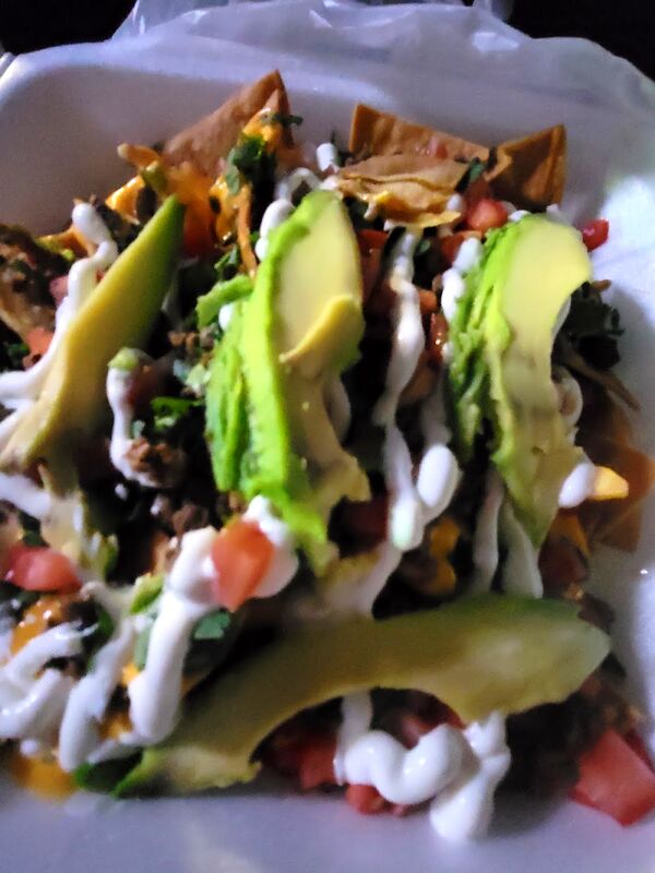Nachos from above, covered in sour cream, avocado and tomato