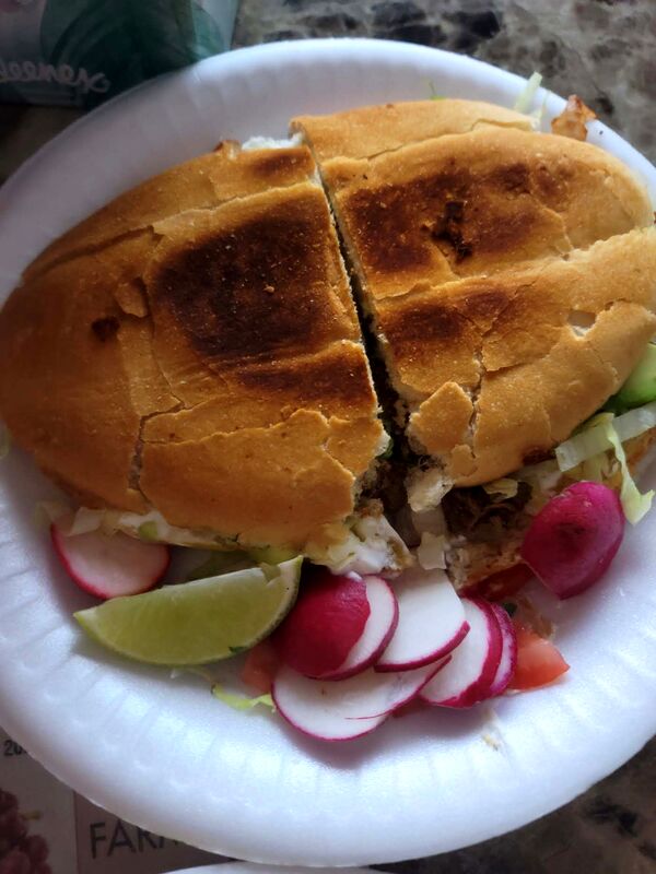 A toasted torta cut in half with radish and lime